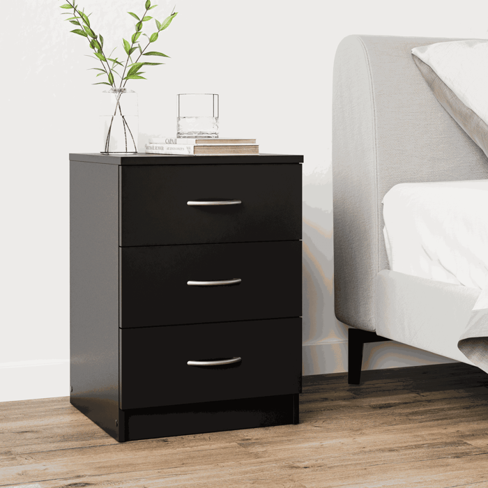 The bedside table ESSENTIAL black with 3 drawers in a cosy bedroom.
