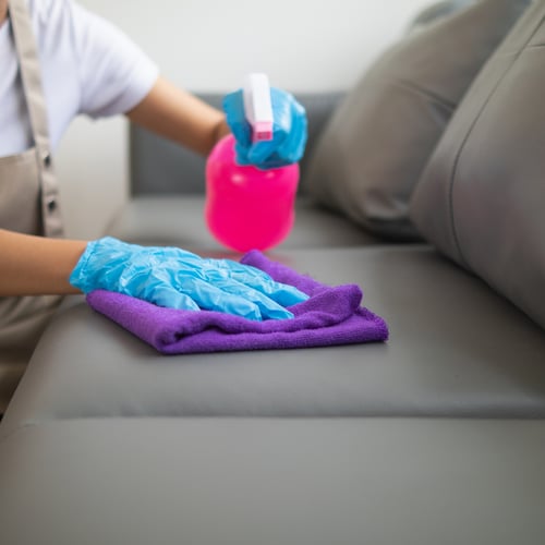 a woman cleaning a sofa with a cloth and detergent