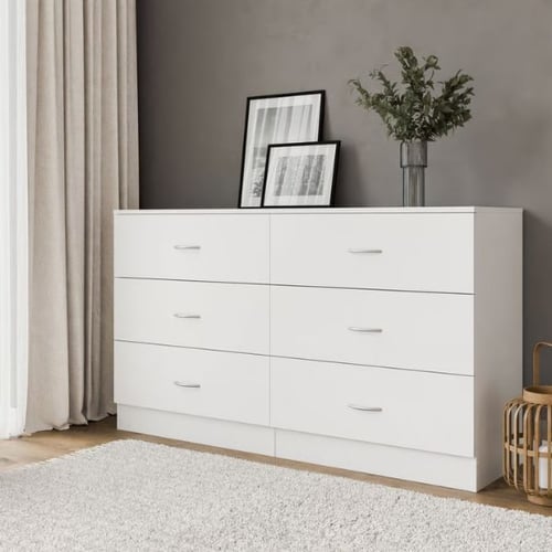 White chest of drawers with framed art and greenery, set against a dark accent wall
